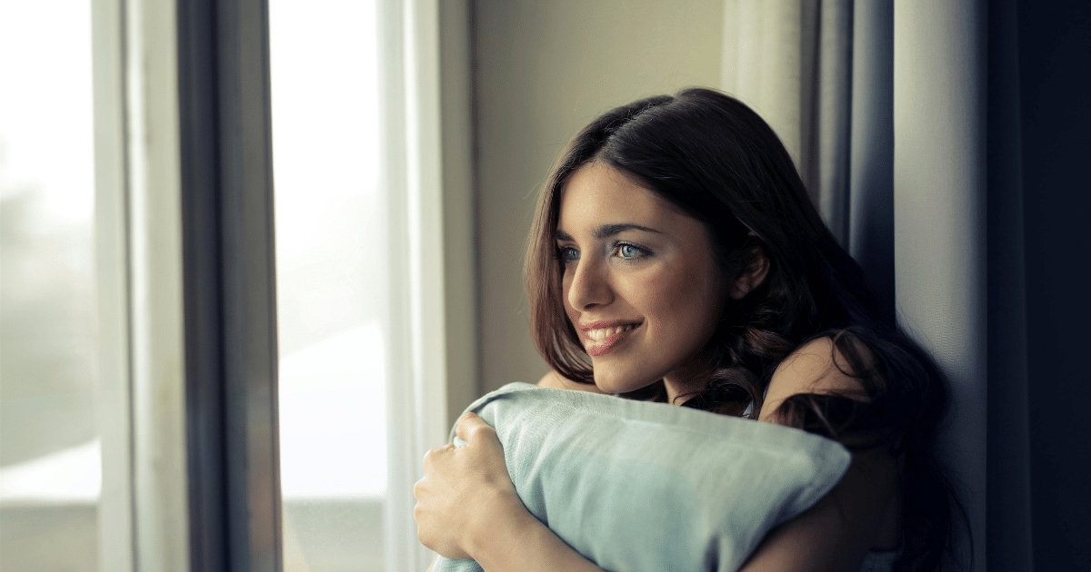 image-19 - California Mental Health Woman seeking grief and loss support, hugging a pillow near a window, contemplating effective therapies for coping.