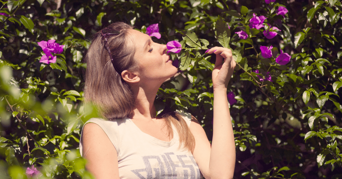 image-3 - California Mental Health Woman smelling purple flowers, a positive psychology technique to enhance mental wellness through sensory experience and nature.