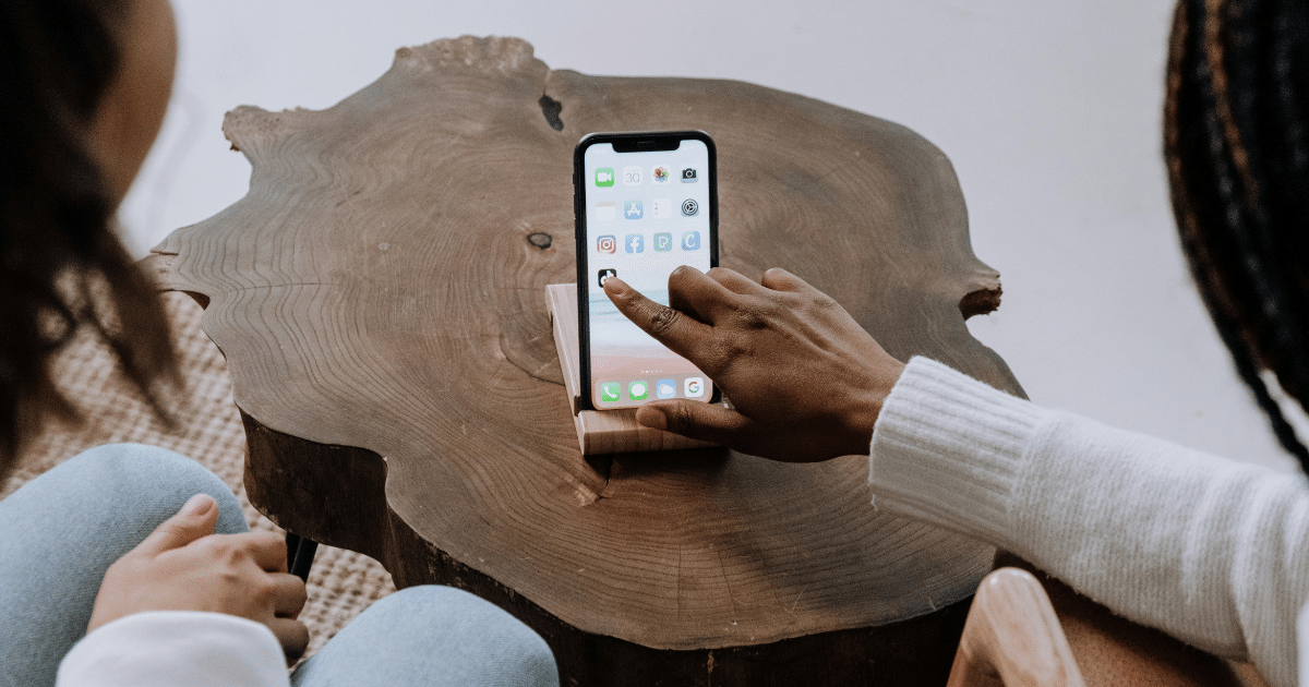 image-5 - California Mental Health Social anxiety help: Person using smartphone on wood table. Get tips and therapy for social anxiety management.
