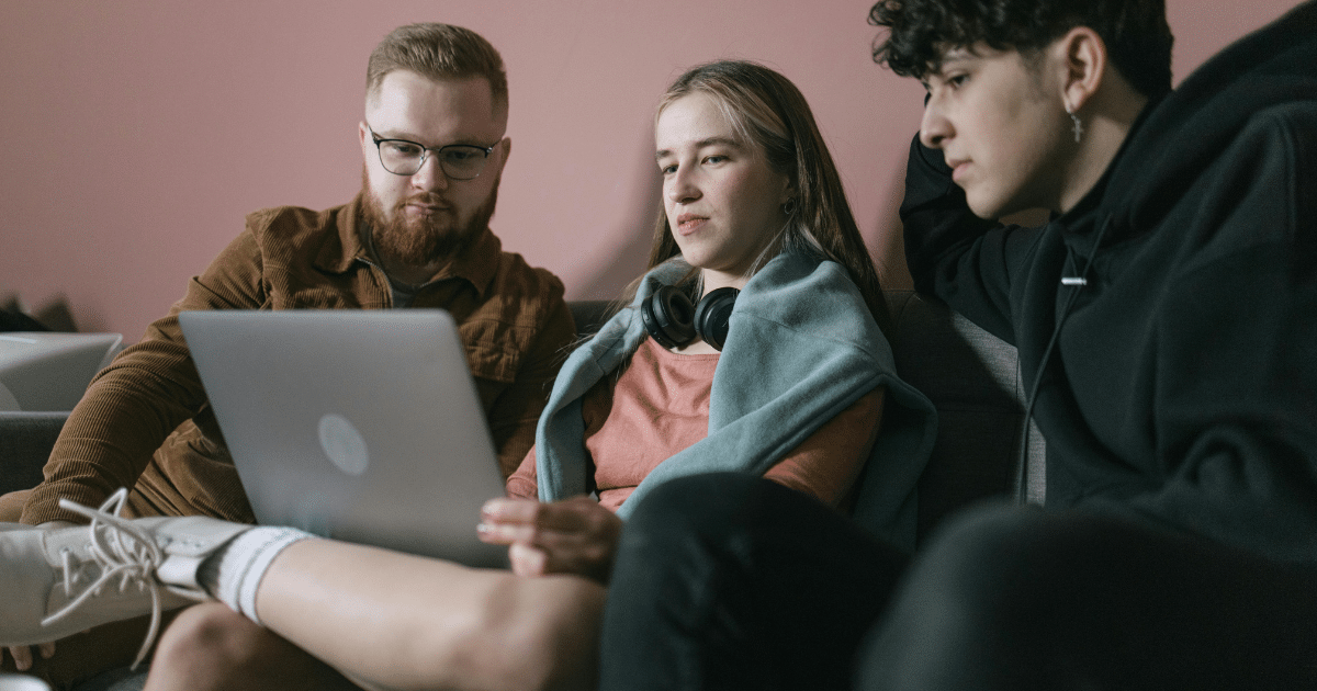 image-6 - California Mental Health Three friends looking at a laptop, possibly seeking social anxiety help and exploring therapy options together.