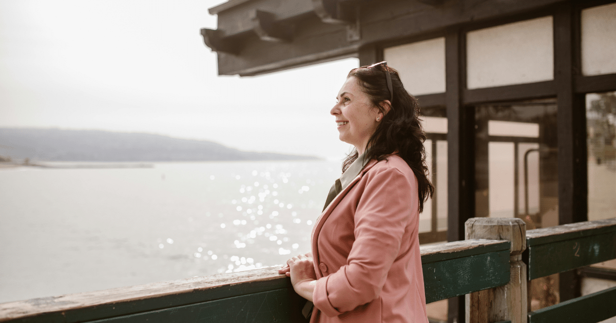 image - California Mental Health Woman practicing positive psychology on pier, enjoying mental wellness by the sea. Techniques for enhanced well-being.