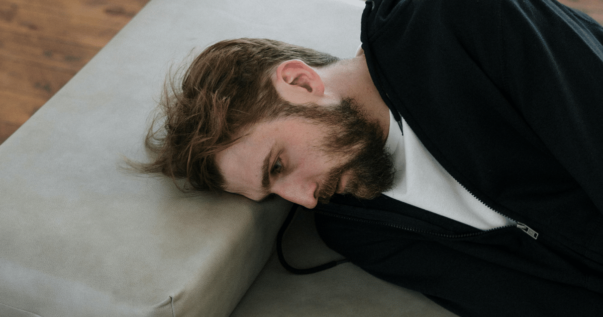 AD_4nXecs_IOr5GICmTaNWkBrBl3fc6eU1OR1OdKe5--qn1Ui6PH2bp-G04dlItJbA98E5iY4SQspkE-vQtjN9ZFh4nCu2AsKE8lAZIQPopUO8nczg6VLKR7cpvx86krrmWitu1jkM8uBQ - California Mental Health Man experiencing mental health challenges during COVID. Bearded man lying down, illustrating stress and pandemic-related wellness issues.