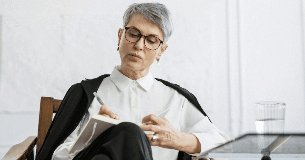 image - California Mental Health Woman in glasses writes in notebook, possibly related to Ganser Syndrome psychological assessment or mental health evaluation.