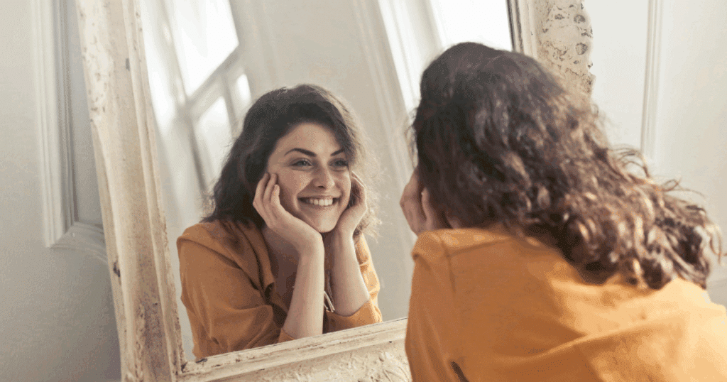 image - California Mental Health Woman smiling at herself in a mirror, a visual representation of positive self-perception and mental health awareness. Depressive personality.
