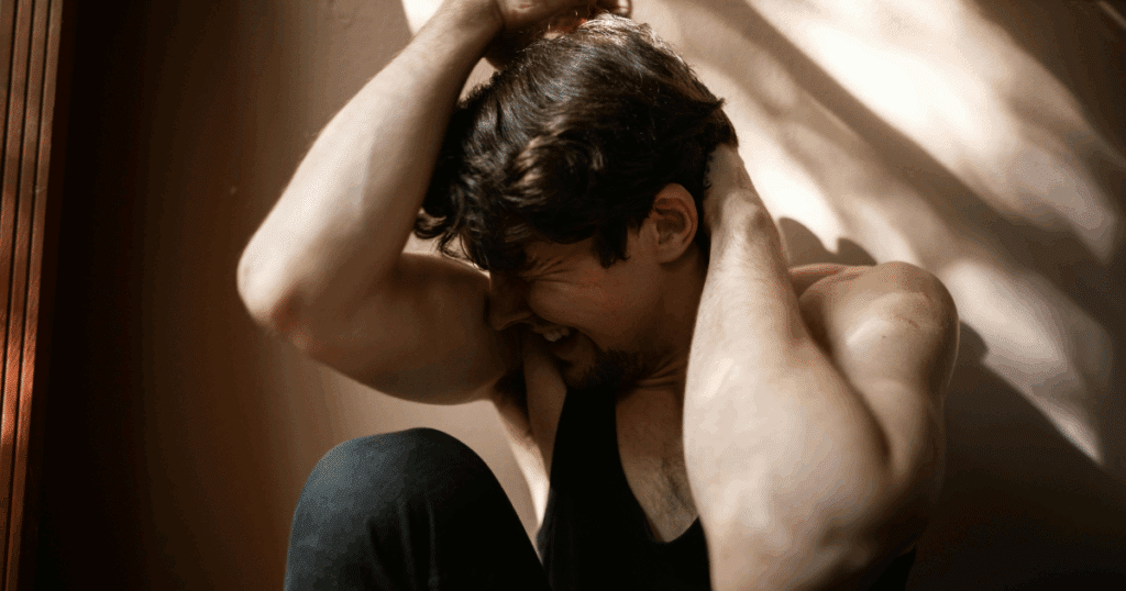 image - California Mental Health Man experiencing PTSD symptoms, holding head in distress. Signs you need professional PTSD help. Mental health and trauma recovery.