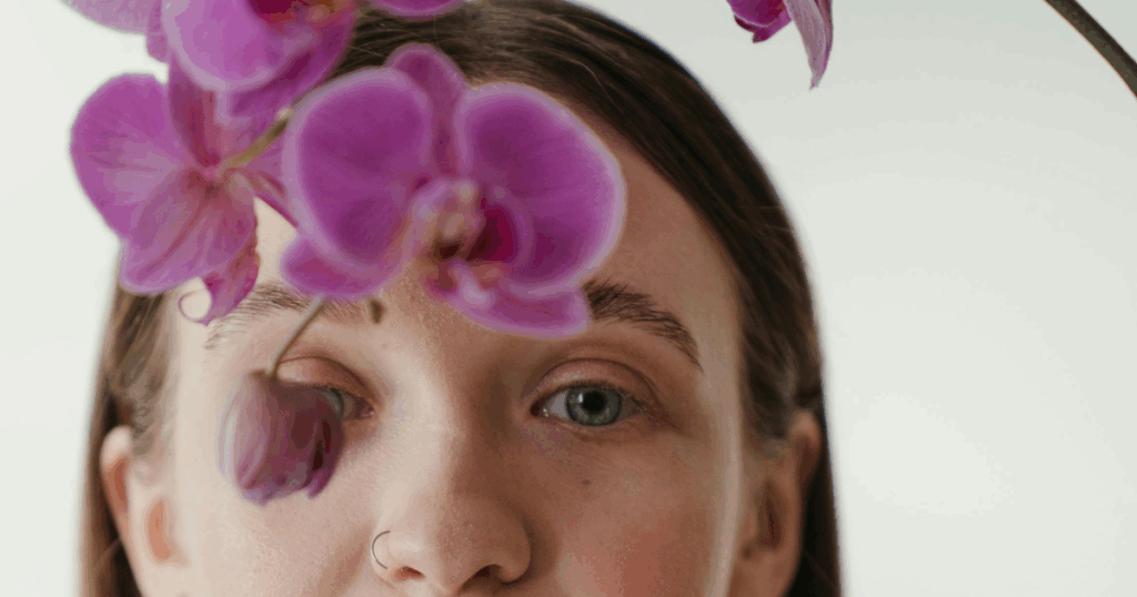 image - California Mental Health Woman's face with purple orchid, exploring alcohol's impact on anxiety. Does alcohol ease or worsen anxiety? Learn more here.