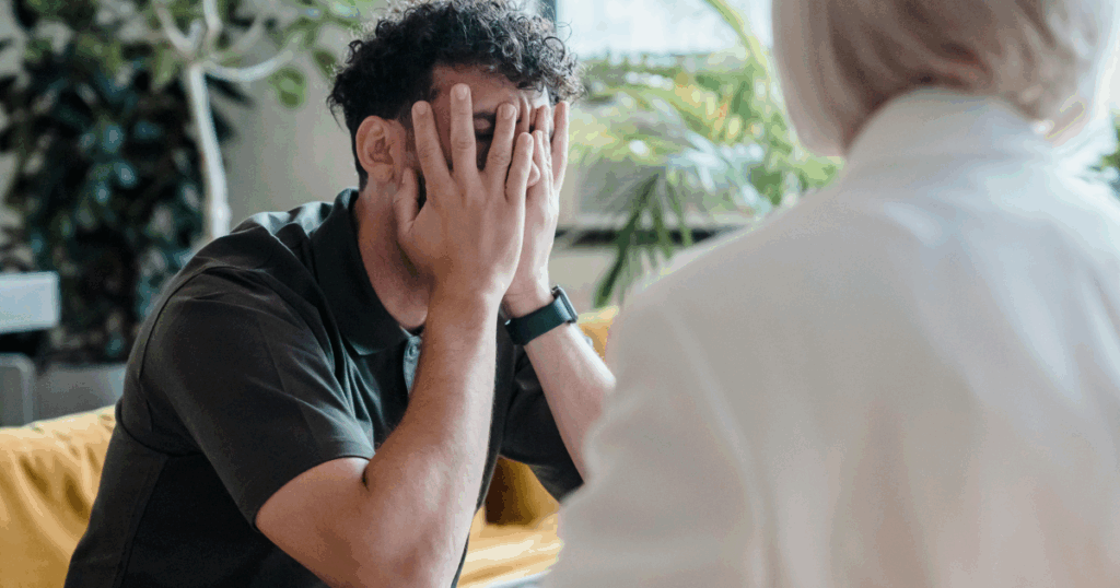 image - California Mental Health Sadistic Personality Disorder: Man with hands covering face during therapy session. Mental health and personality disorder concept.