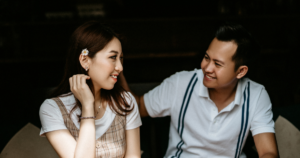 - California Mental Health Two people sit close together, smiling at each other in a cozy outdoor setting, candid moment.