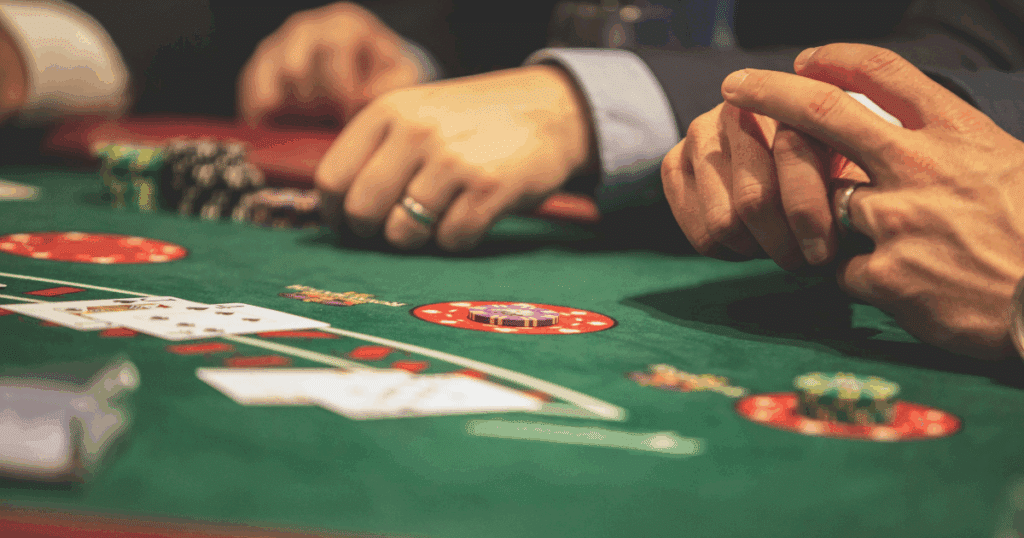Gambling addiction therapy: Close-up of hands playing poker with chips and cards on a green felt table. Risk and addiction concept.