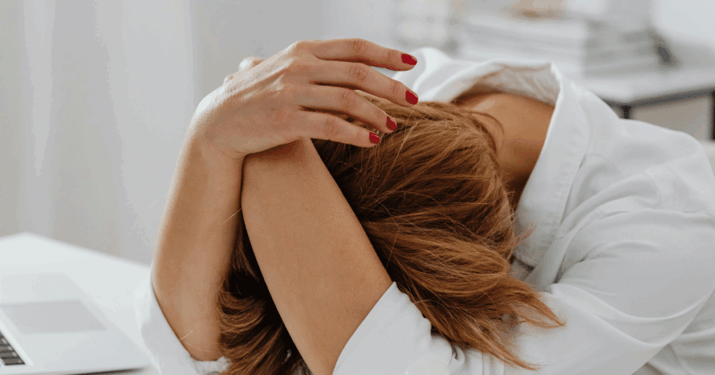 Woman with depression symptoms burying her face in her arms. Adderall may help manage depression symptoms in some cases.