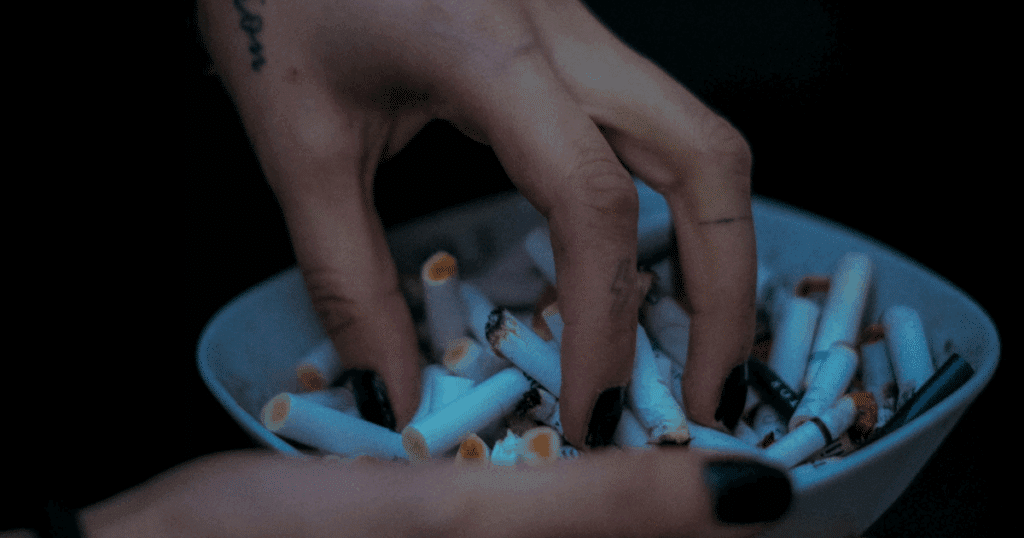 Nicotine addiction: Hands holding ashtray full of cigarette butts, illustrating anxiety and smoking connection.