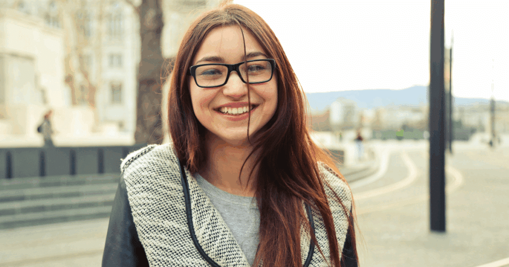 Teenage girl smiling outdoors, fostering growth and confidence. Industry vs. Inferiority support for teens concept.