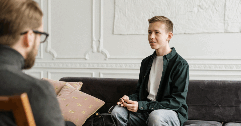 Mental health therapy session: Young man talking to therapist about bystander effect psychology in California.