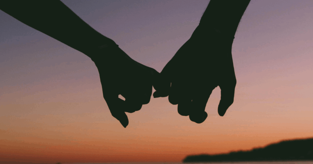 Intimacy and anxiety relief: Silhouette of two people holding pinkies, symbolizing connection, sex and mental wellbeing.